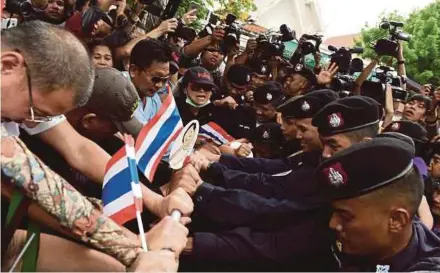  ?? AFP PIC ?? Protesters attempting to break through a phalanx of police outside Thammasat University during a protest to mark the fourth year of junta rule in Bangkok yesterday.