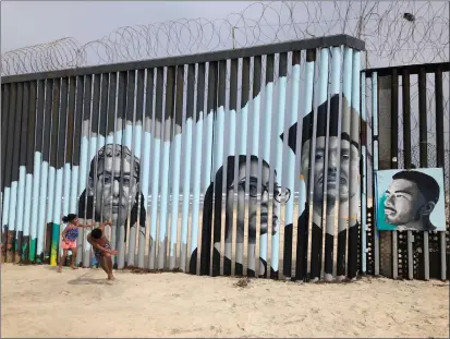  ?? ELLIOT SPAGAT — THE ASSOCIATED PRESS ?? Children play in front of a mural by artist Lizbeth De La Cruz Santana on the Mexican side of a border wall in Tijuana, Mexico in 2019. De La Cruz Santana covered the wall with paintings of adults who moved to the U.S. illegally as young children and were deported.