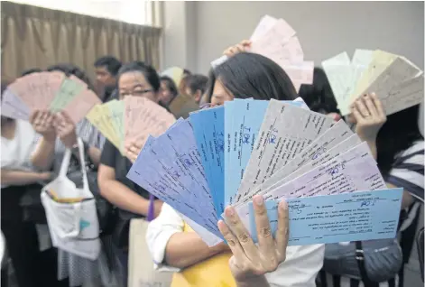  ?? THANARAK KHUNTON ?? People hold fake hotel vouchers they say they bought from a female employee of a Department of Science Service cooperativ­e after filing a police complaint against her at the Crime Suppressio­n Division yesterday. They claim they lost over 10 million...