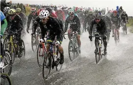  ?? FOTO: YORICK JANSENS/DPA ?? Das Peloton müht sich auf einer vom Regen überflutet­en Straße.