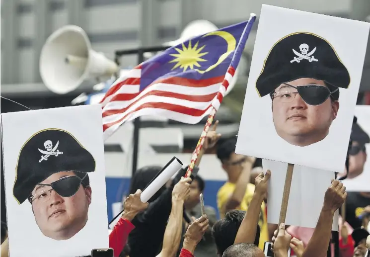  ?? SADIQ ASYRAF/AP FILES ?? Protesters hold portraits of Low Taek Jho, also known as Jho Low, illustrate­d as a pirate during a protest in Kuala Lumpur, Malaysia, in April. He and former Goldman Sachs banker Tim Leissner were charged by the U.S. Justice Department on Thursday in connection to the epic corruption scandal at Malaysia’s state investment fund known as 1MDB.