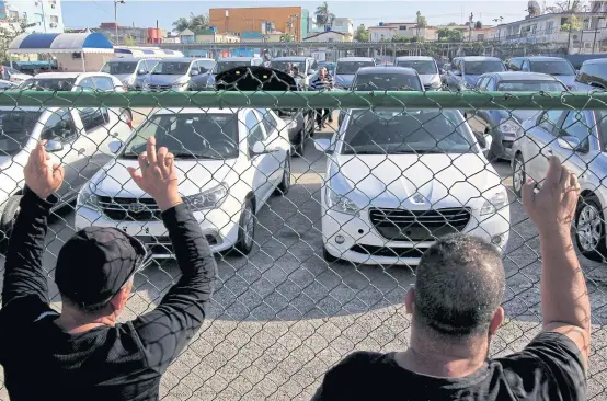  ?? REUTERS ?? People gather outside a government lot where used cars are for sale in Havana on Tuesday.