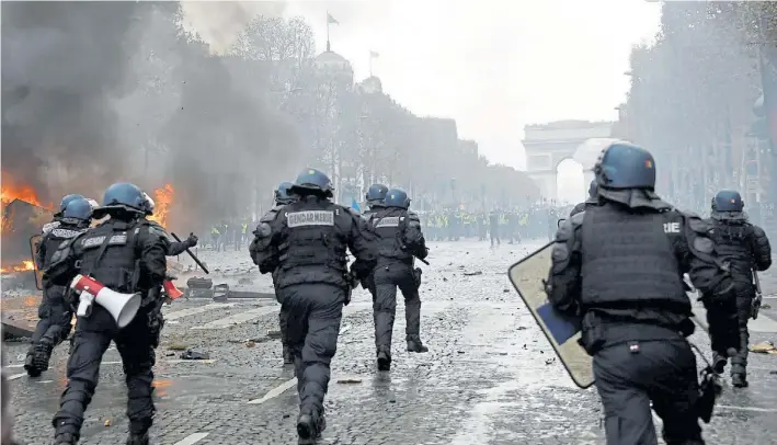  ?? AFP ?? Batalla. Escena de los choques ayer en los Champs Elysees. La policía avanza sobre la calle con escombros. Atrás los manifestan­tes los esperan. Quieren que Macron reflexione.