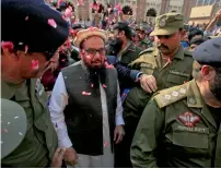  ??  ?? Hafiz Saeed is showered with flower petals as he walks to a court before he was ordered to be released from house arrest in Lahore in November. — Reuters file