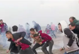  ?? AP FOTO ?? CLASH. Palestinia­n protesters run for cover from teargas fired by Israeli troops during clashes on the Israeli border with Gaza.