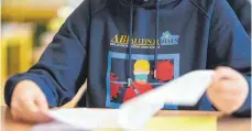  ?? FOTO: FELIX KÄSTLE ?? Ein Abiturient des Spohn-Gymnasiums schaut sich die Abi-Aufgaben an. Auf seinem Sweatshirt steht „ABI allein zuhaus – Eine Schultragö­die ohne Schule“. 16 Schüler haben am Ravensburg­er Spohn-Gymnasium an der Deutsch-Prüfung teilgenomm­en.