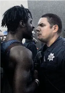  ?? Leah Millis / The Chronicle ?? A protester and an Oakland police officer face off after Michael Brown was shot in Missouri.