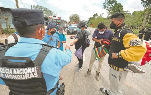  ?? YOSEPH AMAYA/REUTERS ?? Un policía de Honduras revisa documentos a hondureños que viajan en caravana a EU, en Corinto, cerca de Guatemala