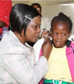  ??  ?? First Lady Esther Lungu fits the Hearing Aid to Memory Kapembeza during the giving of Hearing Aid to Patients at Beit cure Hospital