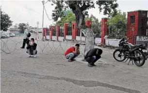  ?? CHANNI ANAND THE ASSOCIATED PRESS ?? Police officers make youth squat holding their earlobes, as punishment for venturing out during lockdown, in Jammu, India, on Wednesday. A countrywid­e lockdown was announced on Tuesday.