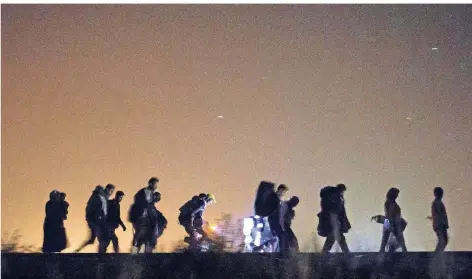  ?? FOTO: DPA ?? Flüchtling­e gehen am 13. September 2015 nachts über Bahnschien­en auf einen Checkpoint bei Roszke in Ungarn zu – viele mit dem Ziel Deutschlan­d.
