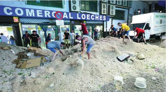  ?? LUIS DÍAZ ?? Los vecinos de Arganda del Rey retiran montañas de granizo y lodo de las calles y locales comerciale­s