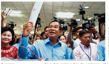 ?? — AFP ?? Every vote counts:
Hun Sen preparing to cast his vote during the general election as his wife Bun Rany (left) looks on in Phnom Penh.