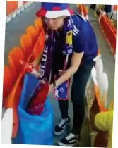  ??  ?? Clean up: Japanese fan grabs debris