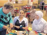  ?? RICK NATHANSON/JOURNAL ?? Lena Braithwait­e, left, a resident at the Brookdale Valencia senior living community in southeast Albuquerqu­e, serves lunch to kitchen staff members Sona Dadullah, center, and Rozia Nisar Ahmed, both from Afghanista­n.