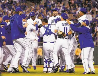  ?? Jamie Squire / Getty Images ?? The Royals gather to celebrate after closer Greg Holland struck out Mike Trout to complete a three-game sweep of the Angels in Kansas City’s first postseason series in 29 years.