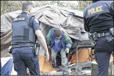  ?? AP ?? Leroy Henry steps out of his tent in the woods to talk with police officers in Everett, where social workers ride along with police to get people connected to help they need.