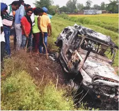  ?? AP ?? Villagers watch a burnt car which run over and killed farmers on Sunday, at Tikonia village in Lakhimpur Kheri.