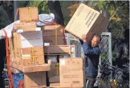  ?? AP PHOTO/ANDY WONG ?? A man loads electronic goods into his tricycle carts on a street in Beijing, Friday. China’s economic growth slowed further in the latest quarter.