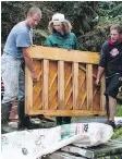  ??  ?? Friends help Steve Gray, right, haul what’s left of his wife’s piano out of his basement after his Arborfield basement was flooded.