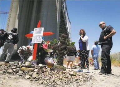  ?? Photos by Paul Chinn / The Chronicle ?? Mourners visit a makeshift memorial site below the Carquinez Bridge in Crockett. Six people have died in three crashes while negotiatin­g a curve with a protective wall only 32 inches high.