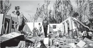  ?? RAMON ESPINOSA/AP ?? George Bolter, left, and his parents walk through the remains of his home destroyed by Dorian, in Freeport, Bahamas.
