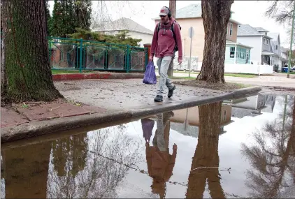  ?? NEWS PHOTO BRENDAN MILLER ?? A person is reflected in a large puddle along Third Street SE following a significan­t downpour that broke the city’s single-day participat­ion record with 73.3 mm of rainfall Tuesday.