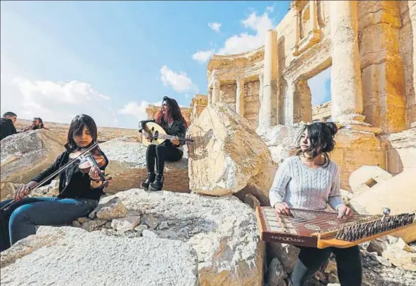  ?? LOUAI BESHARA / AFP ?? Tres jóvenes tocan sus instrument­os, ayer, en el yacimiento de Palmira, recuperado por el Gobierno de Siria el viernes por la tarde