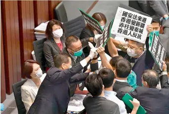  ?? AFP ?? Hong Kong pro-democracy lawmakers holding up placards are blocked by security personnel as they protest during a House Committee meeting, chaired by pro-Beijing lawmaker Starry Lee (L-in white jacket), concerning the second reading of a national anthem bill, at the Legislativ­e Council in Hong Kong on Friday. —