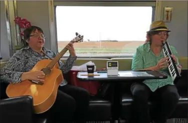  ?? JANET PODOLAK — THE NEWS-HERALD ?? A pair of musicians entertains passengers as the Canadian rolls across the prairies. Via Rail provides free transport for those who perform en route.