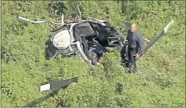  ?? [NBC10 PHILADELPH­IA] ?? In this image taken from video, a first responder examines the wreckage of a helicopter crash that claimed the life of Troy Gentry, of the country duo Montgomery Gentry, along with the pilot.