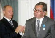  ?? ALEXANDER NENENOV — ASSOCIATED PRESS FILE PHOTO, POOL ?? In this July 25, 2005 file photo, Russian President Vladimir Putin, left, applauds for Alfa Bank head Petr Aven after awarding him with the Order of Merit to the Fatherland during a ceremony at the Kremlin in Moscow. Alfa Group’s owners — Aven, Mikhail Fridman and German Khan — and Russian tech entreprene­ur Aleksej Gubarev all say they had nothing to do with the events described in the “Steele dossier.” In cases playing out in state, federal and British courts, they say they took unfair hits to their reputation­s.