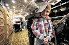  ?? Jon Shapley / Staff photograph­er ?? Sydnee Renfro gives her brother Ezra a kiss as they shop for cowboy hats at the Houston Livestock Show and Rodeo last year.