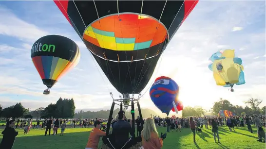  ?? Pictures/Alan Gibson. ?? Crowds watch on as some of the unusual balloons take to the air above Hamilton early yesterday.