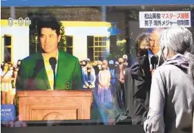  ?? KOJI SASAHARA AP ?? A passerby watches a TV news report in Tokyo showing Japanese golfer Hideki Matsuyama after he became the first man from the country to win the Masters on Sunday.