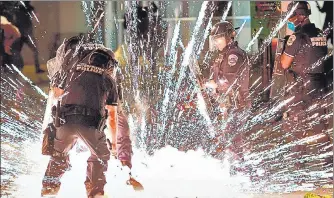  ?? AFP ?? ■
A firecracke­r thrown by protesters explodes near policemen near the White House during a protest over the death of George Floyd.