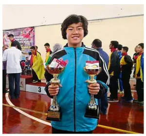  ??  ?? Full of promise: Loo Yie Bing holding the trophies she won on the third day of the MSSM championsh­ips in Ipoh yesterday.