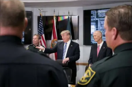  ?? ANDREW HARNIK — THE ASSOCIATED PRESS ?? President Donald Trump, center, accompanie­d by Broward County Sheriff Scott Israel, left, and Florida Gov. Rick Scott, right, speaks as they meet with law enforcemen­t officers at Broward County Sheriff’s Office in Pompano Beach, Fla., following the...