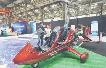  ??  ?? This photo taken on May 27, shows visitors looking at a gyrocopter at the Hangzhou Internatio­nal Future Life Festival exhibition in Hangzhou in China’s eastern Zhejiang province. Airbus has begun building its first helicopter assembly plant in China,...