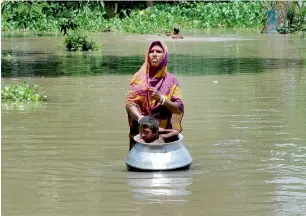  ?? PTI ?? A woman with her child, in a utensil, moves to a safer place from the flood affected Khanamukh village in Morigoan, Assam, on Wednesday. —