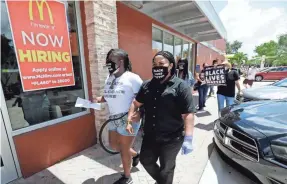  ??  ?? Tifanny Burks, left, a community organizer with Black Lives Matter Alliance Broward, and Deatric Edie, a worker at a McDonald's, enter the restaurant.