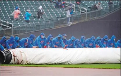  ?? SETH WENIG/AP PHOTO ?? New York Mets employees roll a tarp over the field during a delay in the first inning of a game against the Miami Marlins at Citi Field on Sunday in New York. It’s been the story of the season thus far for the Mets, who have played fewer games than any other team in Major League Baseball after another postponeme­nt Friday in Colorado thanks to a spring snowstorm.