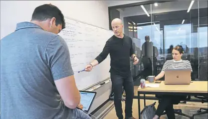  ?? Pam Panchak/Post-Gazette ?? Revtown co-founder and CEO Henry Stafford leads a team meeting in an office in the Industriou­s co-working space, Downtown.
