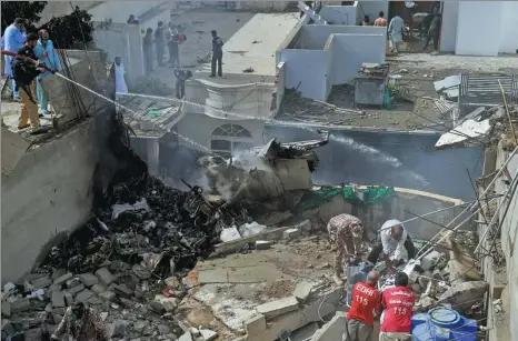  ?? ASIF HASSAN / AGENCE FRANCE-PRESSE ?? Police spray water on part of the wreckage of a Pakistan Internatio­nal Airlines aircraft that crashed in a residentia­l area in Karachi on Friday.