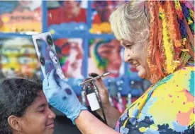  ?? PHOTOS BY MCKENZIE LANGE/INDEPENDEN­T MAIL ?? Julia Jones, with Emeralds Artistry Entertainm­ent out of Columbia, uses a stencil to airbrush a design on Lizeth Perez, 10, in downtown Spartanbur­g during Spring Fling in 2023.