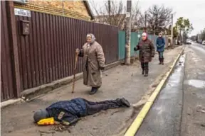  ?? Foto: DANIEL BEREHULAK/THE NEW YORK TIMES ?? Omfattende krigsforbr­ytelser Innbyggere i Butsja i Ukraina går 2. april forbi en død sivil som ligger på gaten.