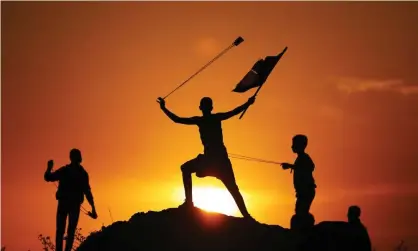  ??  ?? Palestinia­ns throw stones using slingshots in response to Israeli forces’ interventi­on during the 18th ‘maritime demonstrat­ion’ to break the Gaza blockade by sea with vessel near the north coast border in Gaza City. Photograph: Anadolu Agency/Getty Images