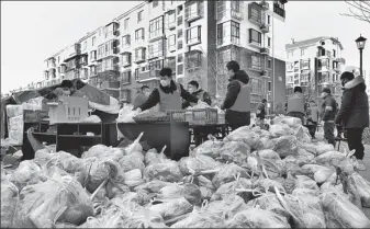  ?? TONG YU / FOR CHINA DAILY ?? Community workers distribute vegetables for quarantine­d residents in Tianjin’s Xiqing district on Wednesday.