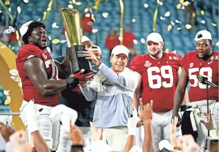  ?? MARK J. REBILAS/USA TODAY SPORTS ?? Head coach Nick Saban and offensive lineman Alex Leatherwoo­d (70) lift the spoils of another college football national championsh­ip for Alabama. The title was Saban’s sixth at the school.