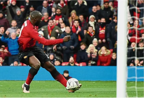  ?? — AFP ?? Right on target: Manchester United striker Romelu Lukaku slots the ball into the net during the English FA Cup third-round match against Reading at Old Trafford yesterday.